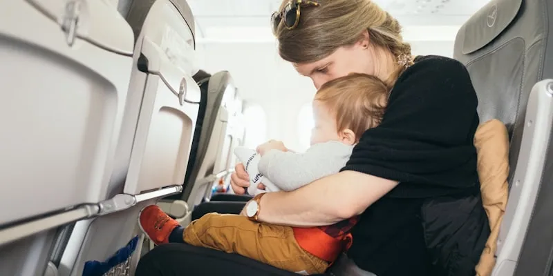 Woman carrying a baby while sitting at an airport gate
